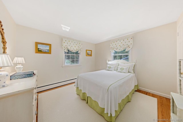 bedroom with light wood-style flooring, baseboards, and baseboard heating