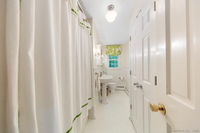 bathroom with tile patterned flooring, baseboard heating, and toilet