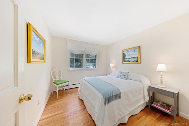 bedroom featuring light wood-style floors, baseboard heating, and baseboards