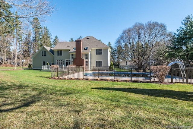 rear view of property featuring a fenced in pool and a yard