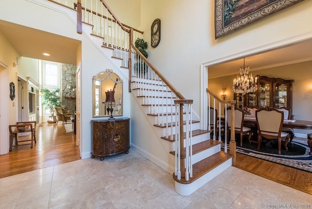 staircase with an inviting chandelier, a towering ceiling, and hardwood / wood-style floors