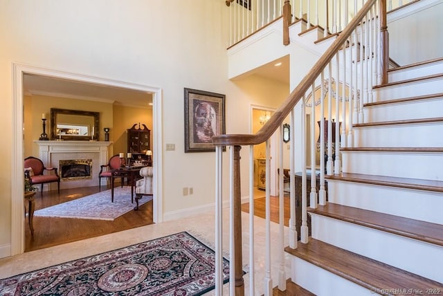 staircase featuring a high ceiling and crown molding