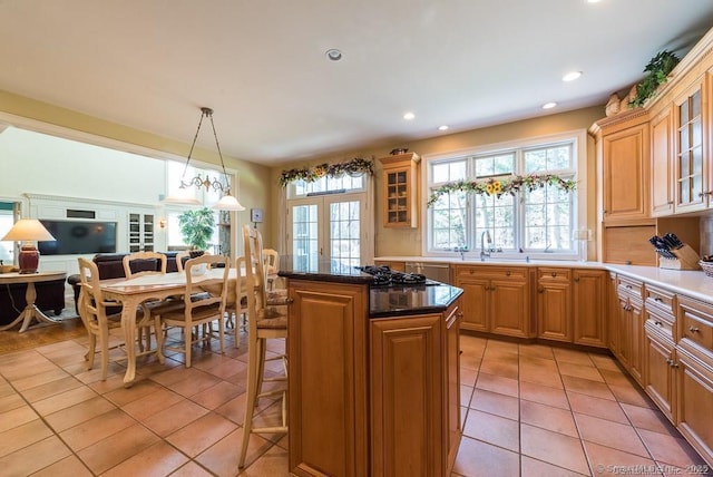 kitchen featuring light tile patterned floors, a kitchen island, a kitchen bar, decorative light fixtures, and french doors