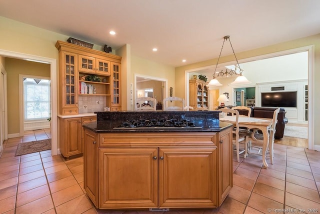 kitchen featuring light tile patterned floors, a center island, decorative light fixtures, black gas stovetop, and dark stone counters