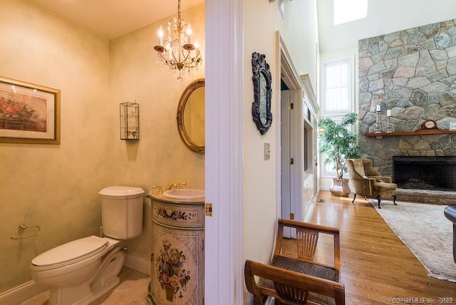 bathroom featuring a fireplace, toilet, hardwood / wood-style floors, and a notable chandelier