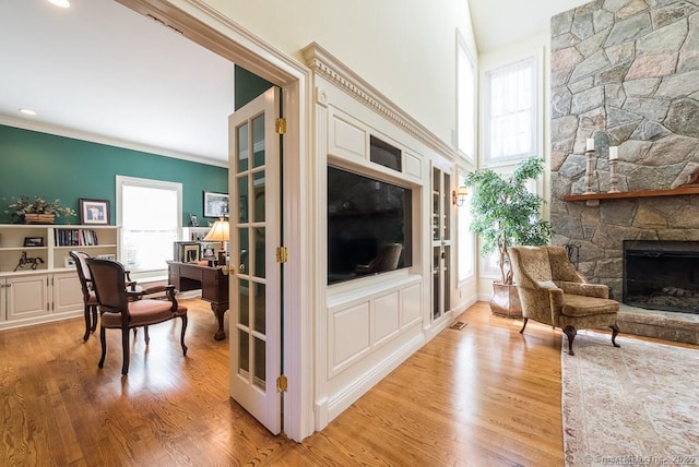 living room featuring crown molding, a fireplace, and light wood-type flooring