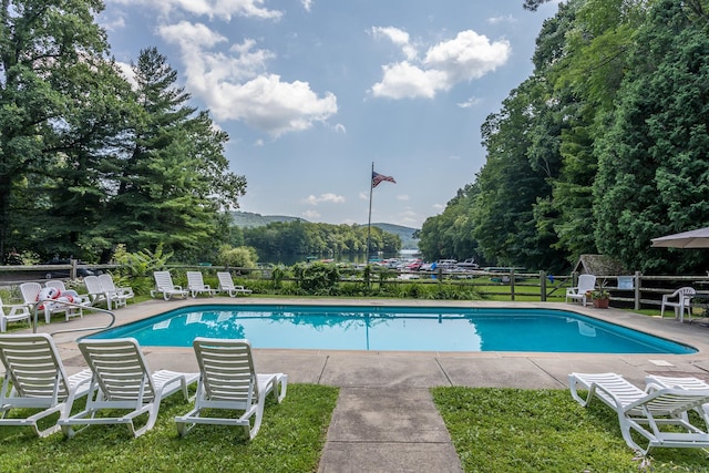 community pool featuring fence, a patio, and a mountain view