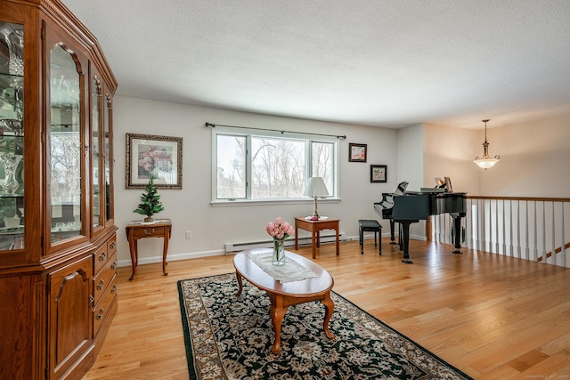 living area featuring a textured ceiling, baseboard heating, light wood-style flooring, and baseboards