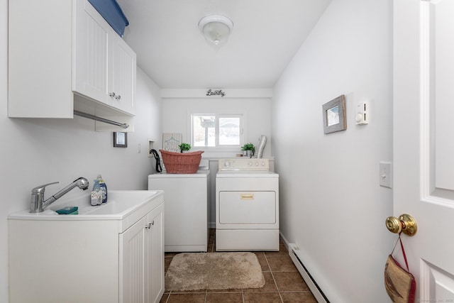 clothes washing area with cabinet space, baseboards, dark tile patterned flooring, washing machine and dryer, and a sink