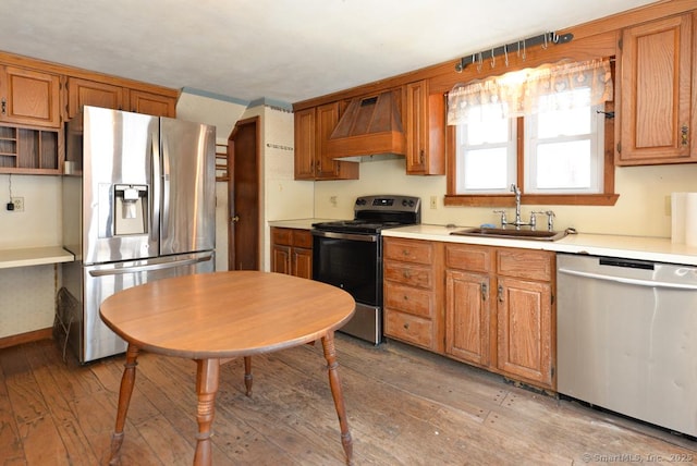 kitchen with sink, light hardwood / wood-style flooring, stainless steel appliances, and custom range hood