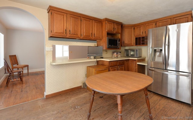 kitchen featuring light hardwood / wood-style flooring, kitchen peninsula, and appliances with stainless steel finishes