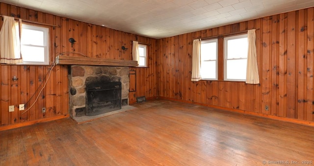 unfurnished living room featuring hardwood / wood-style floors, plenty of natural light, and wood walls