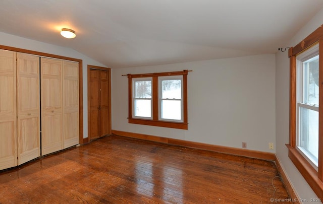 unfurnished bedroom featuring multiple closets, lofted ceiling, and dark wood-type flooring