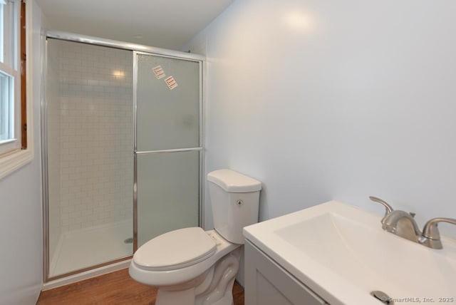 bathroom featuring hardwood / wood-style flooring, toilet, a shower with door, and sink