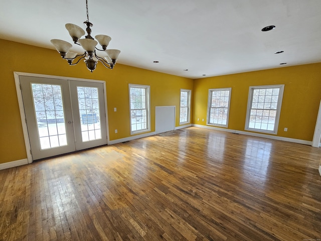 unfurnished room with french doors, wood-type flooring, and a chandelier