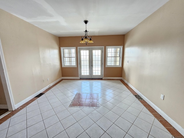 tiled empty room featuring a notable chandelier and french doors