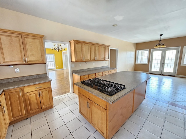 kitchen featuring an inviting chandelier, a healthy amount of sunlight, black gas stovetop, and a kitchen island