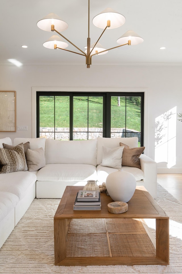 living room with an inviting chandelier, plenty of natural light, and ornamental molding