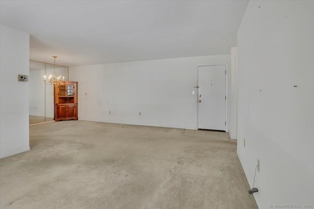 carpeted empty room featuring a chandelier