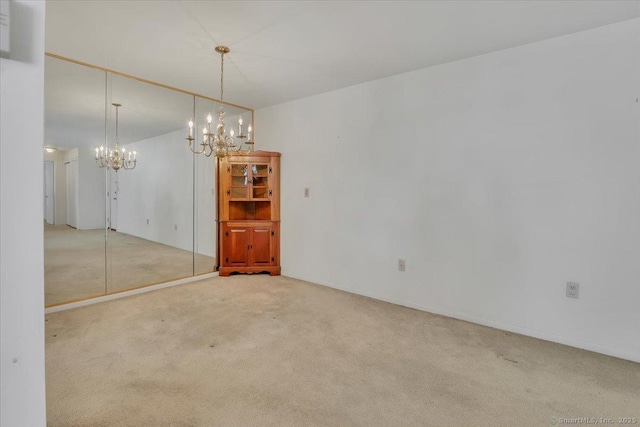 carpeted empty room with an inviting chandelier