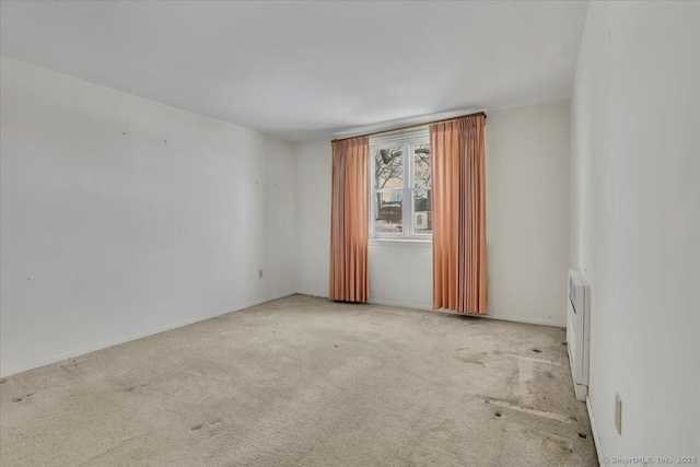 spare room with radiator heating unit and light colored carpet