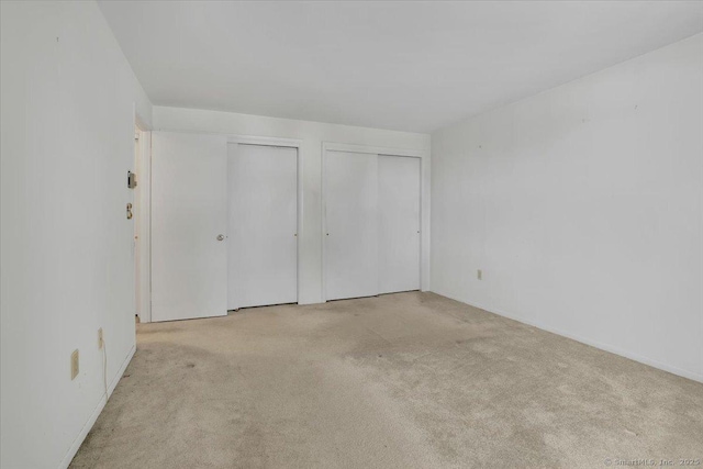 unfurnished bedroom with light carpet and two closets