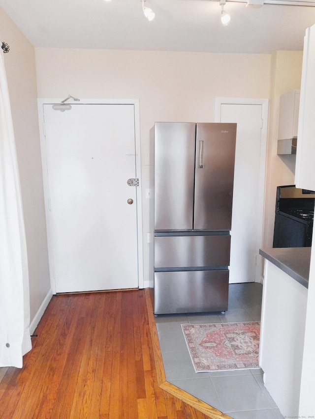 kitchen with white cabinetry, dark hardwood / wood-style floors, stainless steel fridge, and gas range