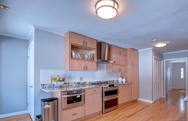 kitchen with wall chimney exhaust hood, light brown cabinets, appliances with stainless steel finishes, light stone countertops, and light hardwood / wood-style floors