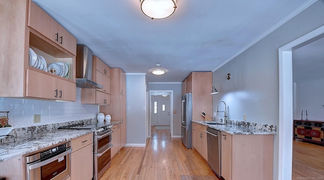 kitchen with appliances with stainless steel finishes, light brown cabinetry, light stone countertops, and wall chimney range hood