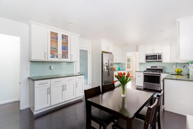 kitchen featuring sink, tasteful backsplash, appliances with stainless steel finishes, dark stone counters, and white cabinets