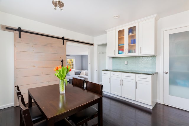 dining area with dark wood-type flooring and a barn door