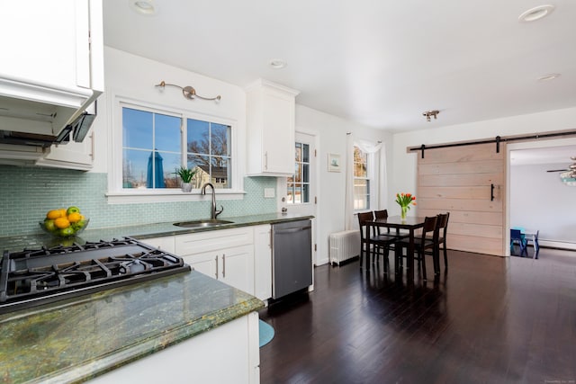 kitchen featuring sink, radiator, dishwasher, white cabinets, and a barn door