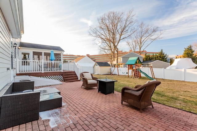 view of patio with a storage unit, a playground, and an outdoor living space with a fire pit