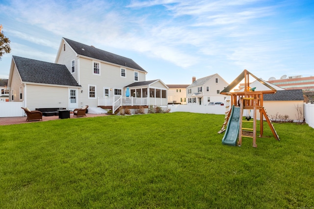 back of house with a sunroom, a yard, an outdoor hangout area, a playground, and a patio