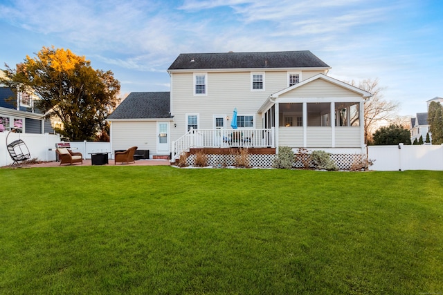 back of house featuring a wooden deck, a lawn, a sunroom, and a patio