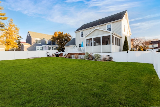 rear view of house featuring a yard and a sunroom