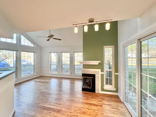 unfurnished living room with plenty of natural light, light wood-style flooring, a fireplace, and high vaulted ceiling