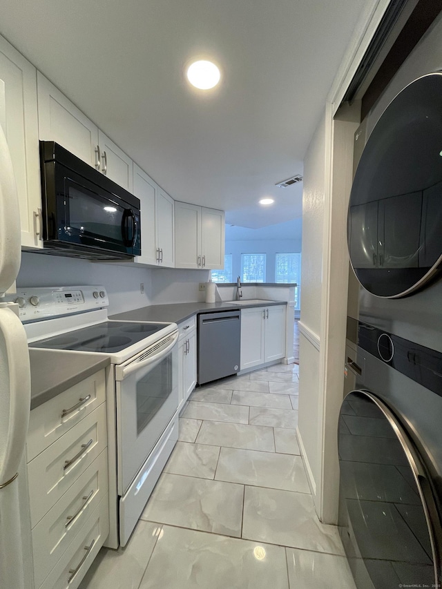 kitchen with white range with electric cooktop, stacked washer and dryer, white cabinetry, black microwave, and dishwasher