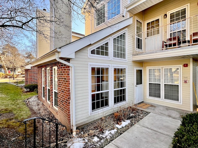 view of property exterior featuring a chimney and brick siding