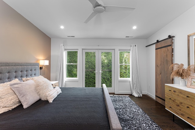 bedroom with dark wood-type flooring, ceiling fan, a barn door, and french doors