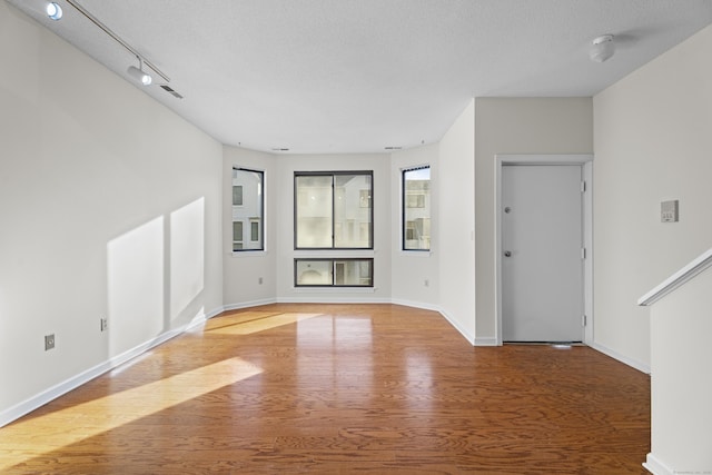 unfurnished living room featuring track lighting, wood-type flooring, and a textured ceiling