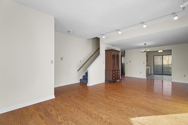 spare room with rail lighting, a notable chandelier, and light hardwood / wood-style flooring