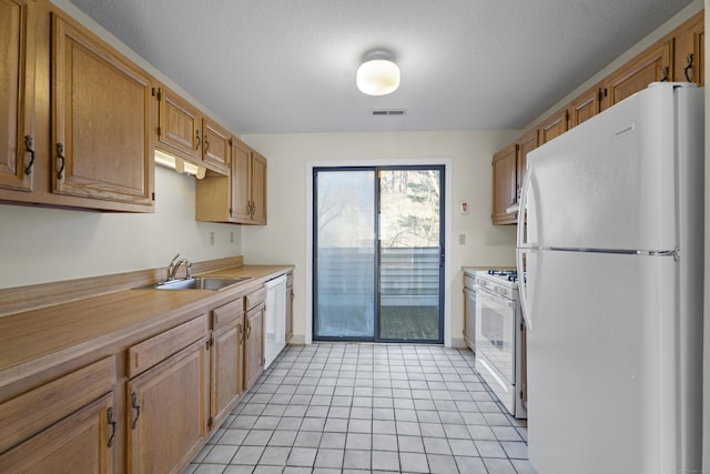 kitchen with sink, white appliances, light tile patterned floors, and a textured ceiling