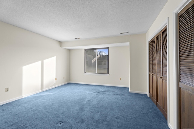 unfurnished bedroom with a textured ceiling, multiple closets, and carpet