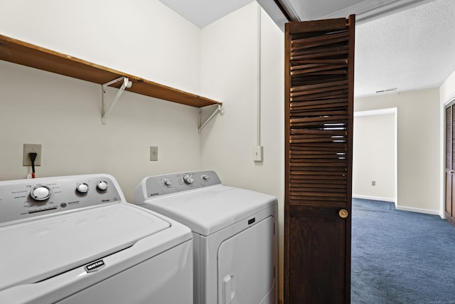 clothes washing area featuring a textured ceiling, washing machine and clothes dryer, and carpet flooring