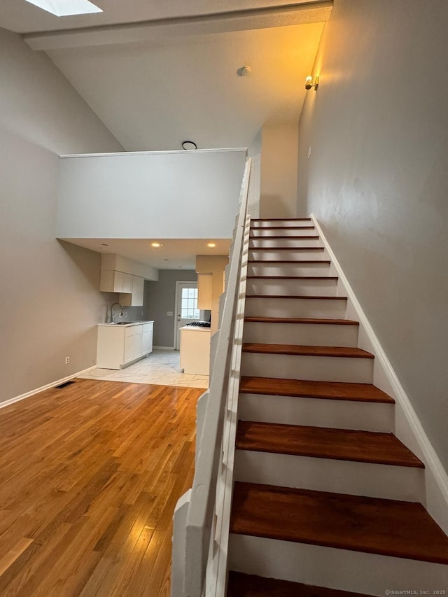 stairs featuring sink, hardwood / wood-style floors, and a skylight