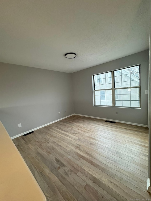 empty room with light hardwood / wood-style flooring and a textured ceiling