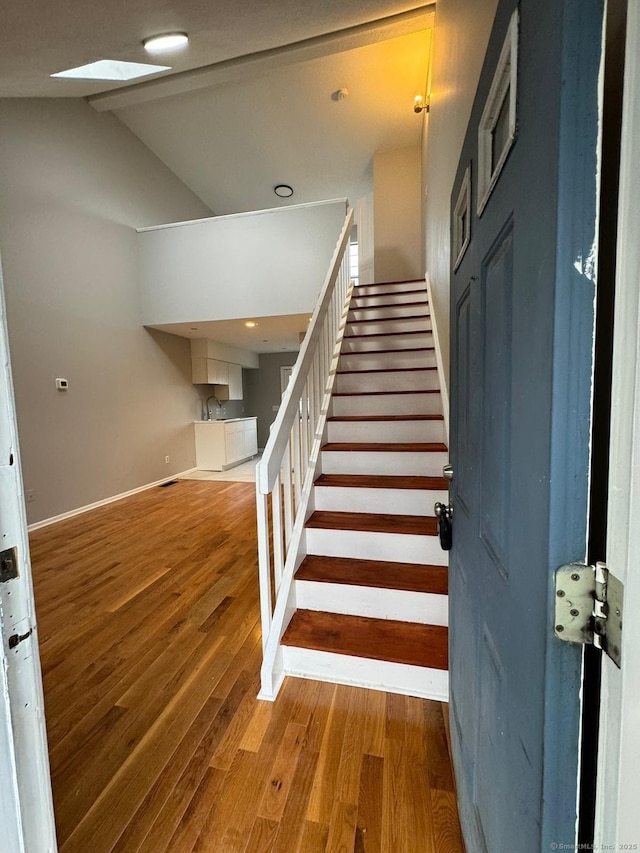 staircase with lofted ceiling and hardwood / wood-style floors