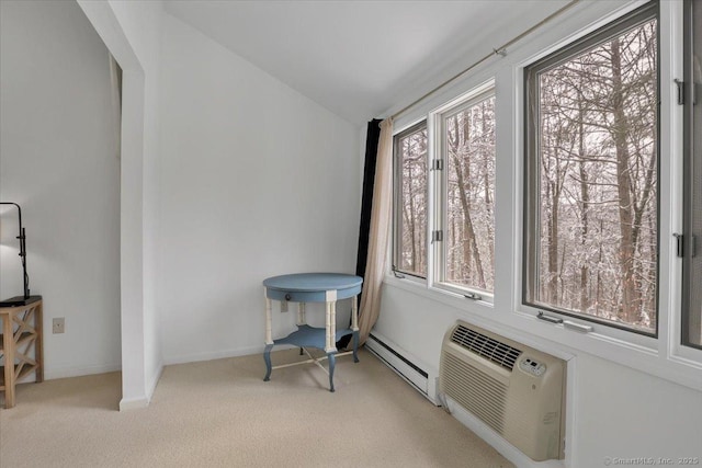 interior space with light colored carpet, lofted ceiling, a baseboard radiator, and an AC wall unit