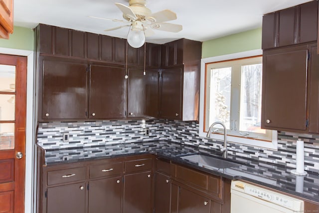 kitchen featuring sink, dark stone countertops, dark brown cabinets, white dishwasher, and decorative backsplash
